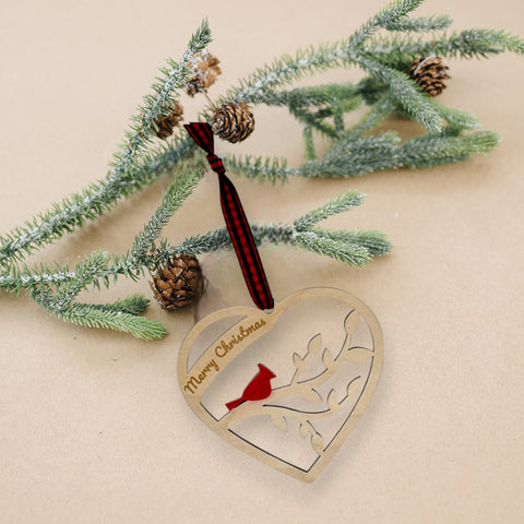 A wooden heart-shaped ornament adorned with intricate carvings. The words 'Merry Christmas' are elegantly engraved across the top of the heart. This memorial ornament captures the spirit of Christmas with its heartfelt design.