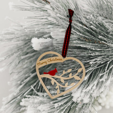 A wooden heart-shaped ornament adorned with intricate carvings. The words 'Merry Christmas' are elegantly engraved across the top of the heart. This memorial ornament captures the spirit of Christmas with its heartfelt design.