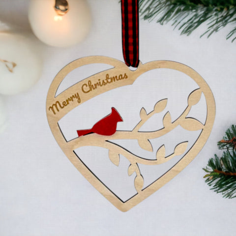 A wooden heart-shaped ornament adorned with intricate carvings. The words 'Merry Christmas' are elegantly engraved across the top of the heart. This memorial ornament captures the spirit of Christmas with its heartfelt design.