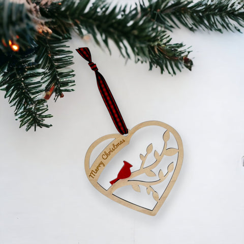 A wooden heart-shaped ornament adorned with intricate carvings. The words 'Merry Christmas' are elegantly engraved across the top of the heart. This memorial ornament captures the spirit of Christmas with its heartfelt design.