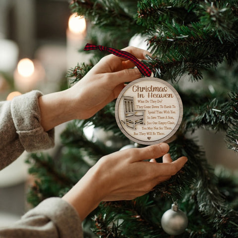 Officially licensed Christmas in Heaven memorial wooden ornament by John F Connor, featuring a poignant chair design with the iconic 'Christmas in Heaven' poem. A heartfelt remembrance gift for the holiday season, this maple and walnut ornament can be personalized on the back with any name or phrase. Versatile for use as a tree ornament or a year-round display, it serves as a touching sympathy gift, preserving cherished memories with enduring grace.