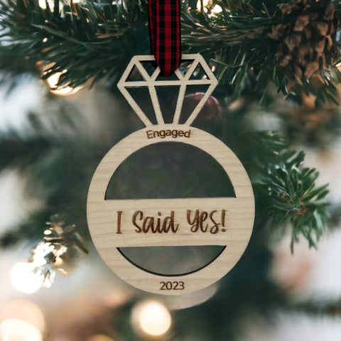 I Said Yes Engaged Ornament - Commemorate the joyous occasion with this charming ornament, symbolizing the beginning of a beautiful journey together. Adorn your tree with this special keepsake, celebrating the excitement of your engagement during the holiday season.