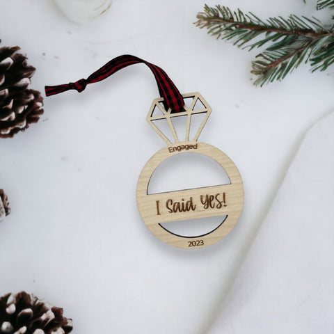 I Said Yes Engaged Ornament - Commemorate the joyous occasion with this charming ornament, symbolizing the beginning of a beautiful journey together. Adorn your tree with this special keepsake, celebrating the excitement of your engagement during the holiday season.